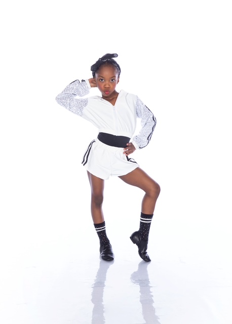Peyton in a white hip-hop outfit striking a pose in the studio